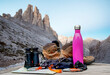 Trekking equipment with water bottle, binoculars and boots in front of the alpine peaks