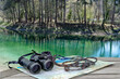 hike in the woods. Map binoculars and rope in front of the forest pond.