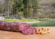 Snack by the blue lake in the woods. Sliced salami and bread biscuits