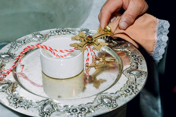 A golden cross in the hand of a priest and two golden crosses on reflective plate in an Apostolic church