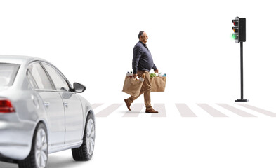 Wall Mural - Car approaching on the street and a mature man carrying grocery bags and crossing at pedestrian zebra