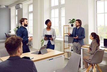 Wall Mural - Team of business people having a work meeting. Group of diverse mixed race men and women meet in the office, talk about current projects, listen to the manager and discuss their future strategy