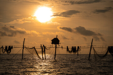 Silhouette of fishermen pulling a nets on fishing poles at sea in Tra Vinh province, Vietnam, Asia during sunrise, local people call it is Day hang khoi.