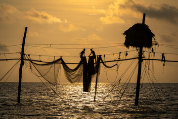 Silhouette of fishermen pulling a nets on fishing poles at sea in Tra Vinh province, Vietnam, Asia during sunrise, local people call it is Day hang khoi.