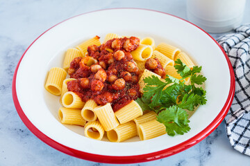 Canvas Print - Vegan rigatoni pasta with chickpeas and tomato sauce in white plate.