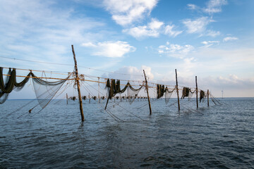 Silhouette of fishermen pulling a nets on fishing poles at sea in Tra Vinh province, Vietnam, Asia during sunrise, local people call it is Day hang khoi.