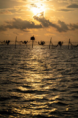 Silhouette of fishermen pulling a nets on fishing poles at sea in Tra Vinh province, Vietnam, Asia during sunrise, local people call it is Day hang khoi.