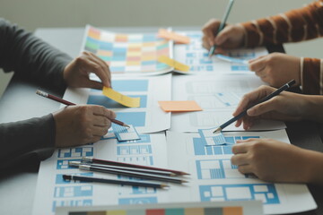 Close up ux developer and ui designer brainstorming about mobile app interface wireframe design on table with customer breif and color code at modern office.Creative digital development agency