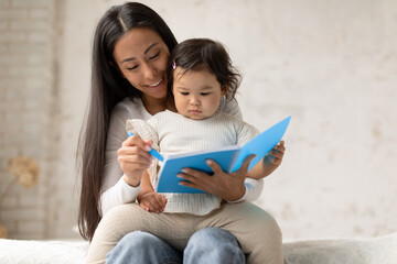 Wall Mural - Asian Mother And Baby Daughter Drawing In Notebook In Bedroom