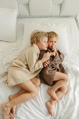 Wall Mural - Boys, brothers lie on the bed in dressing gowns after a shower