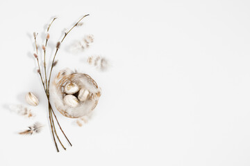 Wall Mural - Easter holiday composition.Top view of Easter eggs in nest, feathers, rabbit, willow plant branches on light beige and white background. Minimal concept Easter. Flat lay, copy space