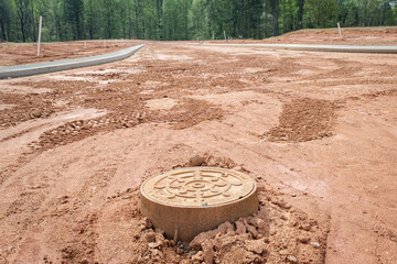 New home residential subdivision development manhole cover and concrete curbs.