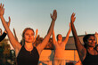 © Maskot - Woman with arms raised exercising with female friend at sunset