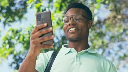 Canvas Print - Video call, black man and waving in a city street, happy and smile on commute or during travel. Hello, smartphone and african businessman in online conference for meeting or negotiation outdoors