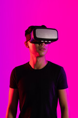 Canvas Print - Asian man using vr headset in studio with purple light and copy space