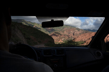 Wall Mural - Journey. View from inside the car, of a man driving along the road across the rocky mountains. 