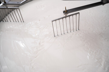 Wall Mural - Milk mixing in curd preparation tank at cheese factory, close up. Cheesemaking process heating milk