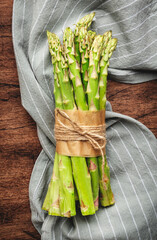 Wall Mural - Fresh asparagus bunch and gray napkin on rustic wooden kitchen table background, top view, copy space