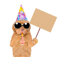 Poster - Mastiff puppy wearing sunglasses and party cap blows into party horn and shows empty placard. isolated on white background