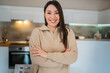 © Sandra - One young woman brunette caucasian standing at home in the kitchen, indoor portrait