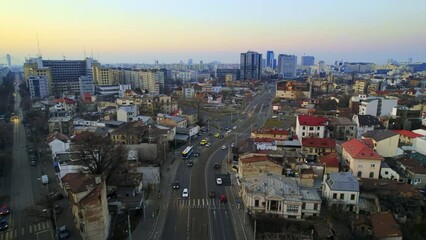 Wall Mural - Aerial drone view of Bucharest at sunset, Romania. Multiple modern and old buildings, moving cars