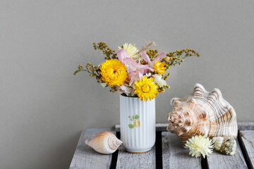 Wall Mural - A bouquet with helichrysum bracteatum - everlasting flower and sea shells on the table.