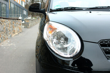 Close-up front headlight with xenon light of black modern car.