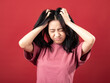© Daniel - A portrait of a young Indonesian (Asian) woman wearing a pink shirt, looking dizzy and holding her head with both hands. Isolated with a red background