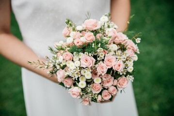 Wall Mural - Top view of the flower bouquet in the bride hands in the garden with blur background
