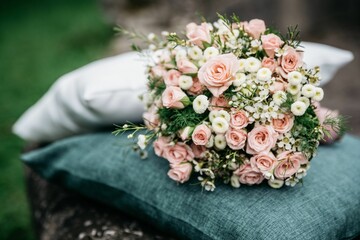 Wall Mural - Closeup shot of the pink and white flowers bouquet on a gray pillow with blur background