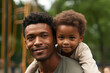 Cute boy sitting on happy African American father's shoulders at park during sunset. Father's Day concept. Generated AI.