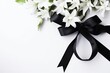 Funeral symbols. White flower near black ribbon on white background top view space for text