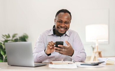 Wall Mural - Portrait of handsome African black young business man working on laptop at office desk.