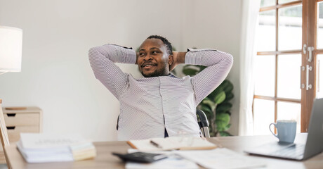 Wall Mural - Portrait of handsome African black young business man working on laptop at office desk.