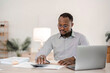 © wichayada - Portrait of handsome African black young business man working on laptop at office desk.
