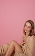 © Anhelina Tyshkovets - beautiful sexy blonde girl on pink background studio shot. A girl wrapped in a beige cloth sits on a pink background. beautiful girl model with make-up, stylish shooting