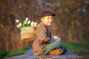 Wall Mural - Beautiful stylish toddler child, boy, playing with Easter decoration in the park, springtime