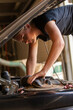 © Austockphoto - young female tradesperson mechanic fixing car engine in automotive repair garage