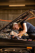 © Austockphoto - young australian tradesperson mechanic fixing car engine in automotive repair garage
