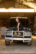 © Austockphoto - Woman mechanic sitting on a car in need of repair in workshop with open bonnet hood