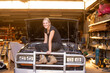 © Austockphoto - Woman mechanic sitting on a car in need of repair in workshop with open bonnet hood