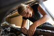 © Austockphoto - Happy young australian tradesperson mechanic fixing car working under bonnet on engine