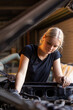 © Austockphoto - young female australian tradesperson mechanic working on car engine in auto repair garage