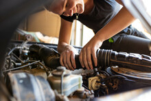 Young Female Tradesperson Mechanic Fixing Car Engine In Automotive Repair Garage