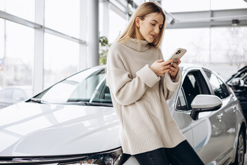 Wall Mural - Young woman talking on the phone in car showroom