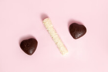 Two Chocolate Hearts And A Coconut Roll On Pink Background