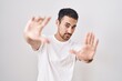 © Krakenimages.com - Handsome hispanic man standing over white background doing frame using hands palms and fingers, camera perspective