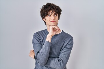 Poster - Young man standing over isolated background with hand on chin thinking about question, pensive expression. smiling and thoughtful face. doubt concept.