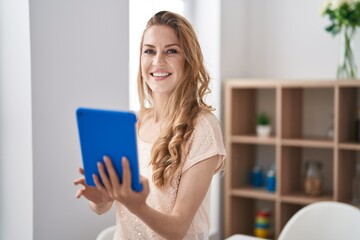 Wall Mural - Young blonde woman smiling confident using touchpad at home