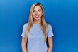 © Krakenimages.com - Beautiful blonde woman wearing casual t shirt over blue background with a happy and cool smile on face. lucky person.